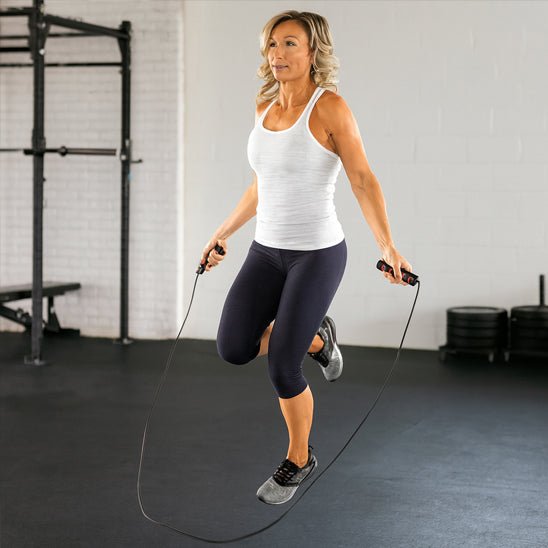 Femme utilisant corde a sauter ajustable pour entraĂźnement cardio fitness maison