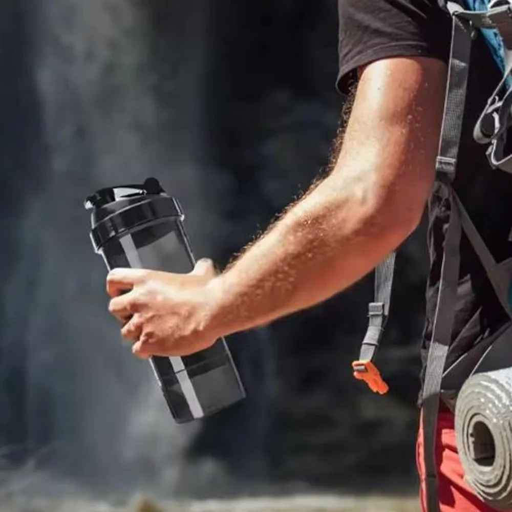 Main tenant le shaker avec compartiment, montrant sa taille ergonomique