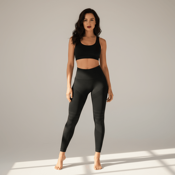 Photo principale : femme portant un legging anti cellulite push up noir Positiflow taille haute, fond ivory gris