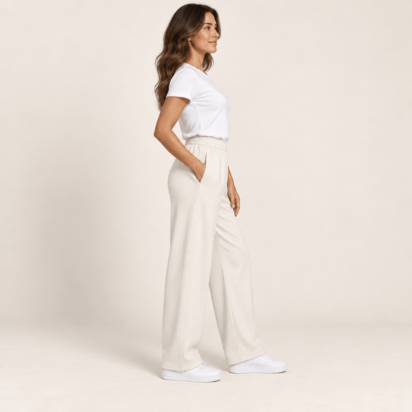 Pantalon sport chic femme ivoire vu de profil, jambe large et tombé droit sur des baskets blanches