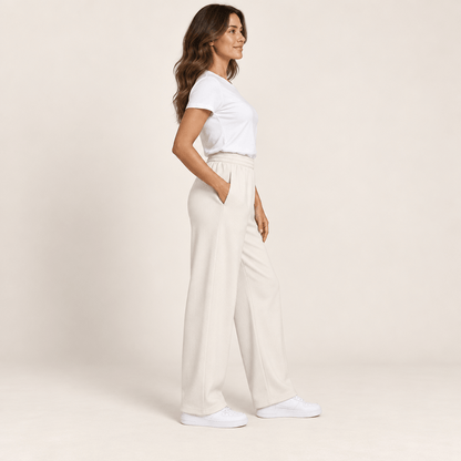 Pantalon sport chic femme ivoire vu de profil, jambe large et tombé droit sur des baskets blanches