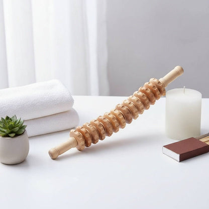 Rouleau en bois ondulé pour massage corporel posé sur une table blanche, avec serviettes, plante succulente, bougie et petit livre de soins. Pack Positiflow : Protocole Peau Lisse & Tonique.