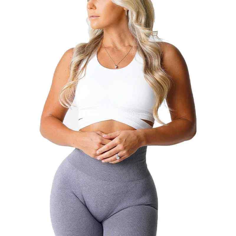 Brassière sport sans couture blanche, crop top avec bandes latérales, portée par une femme, haut près du corps et leggings gris taille haute.