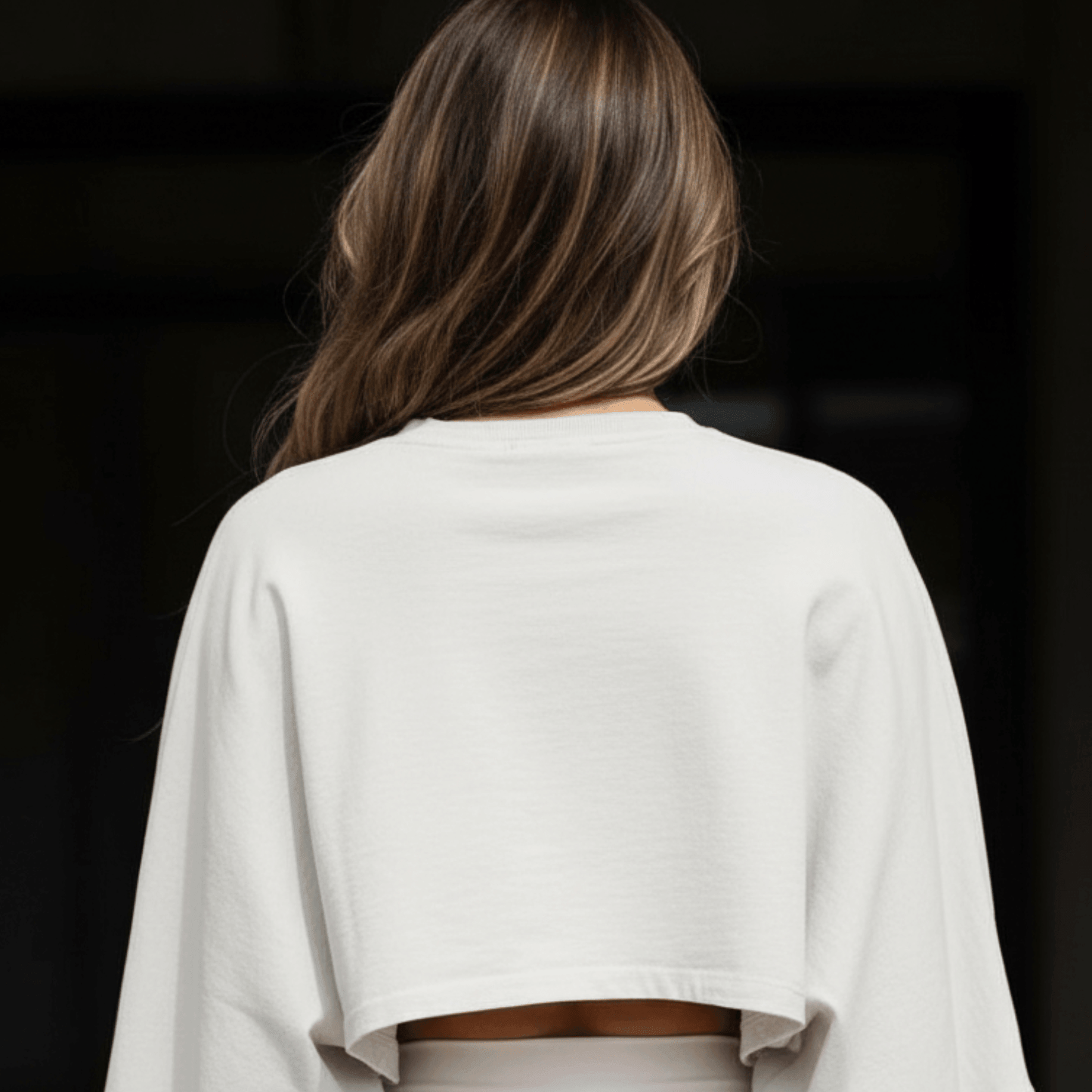Haut court blanc à manches longues porté par une personne vue de dos, cropped crop top femme sport, détail envers le bas du dos.
