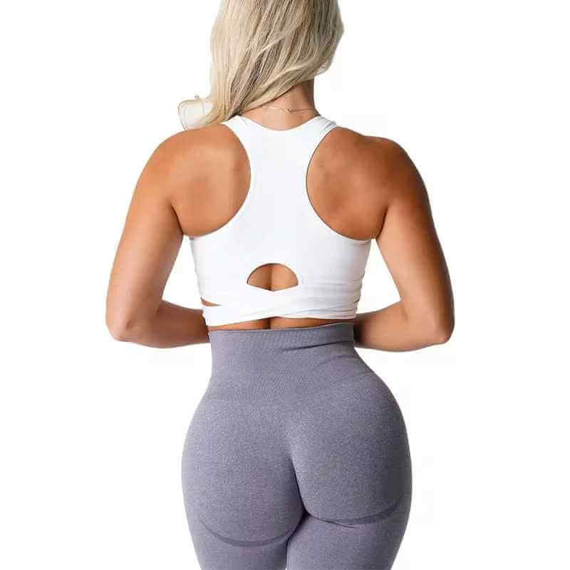 Brassière sport sans couture avec croisement de bretelles, vue arrière d’une femme portant legging gris et haut blanc; XS-L disponible.