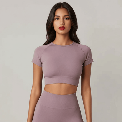 Crop top sans couture sport, tee shirt court femme en gris pâle porté par une mannequin debout, look fitness.