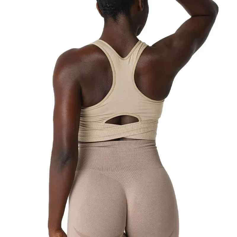 Brassière sport sans couture pour femme avec dos croisé et coupe abdomenale, vue de dos sur mannequin portant pantalon taille haute beige.