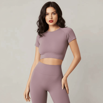 Tee-shirt court femme sans couture sport en mauve, crop top ajusté avec leggings assortis, mannequin pose frontale. Typé fitness.