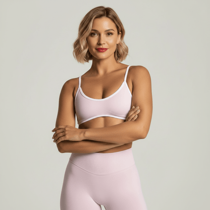 Brassiere sport rose pâle avec finitions blanches portée par une femme en studio premium sur fond anthracite