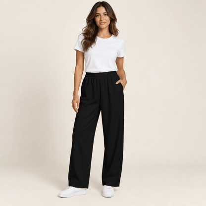 Pantalon sport femme noir à jambe large, taille élastique et poches latérales, porté de face