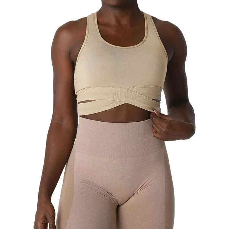 Brassière sport sans couture avec bretelles croisées, modèle femme, beige, montre une ceinture abdominale croisée sur le torse et des leggings assortis; XS-L.