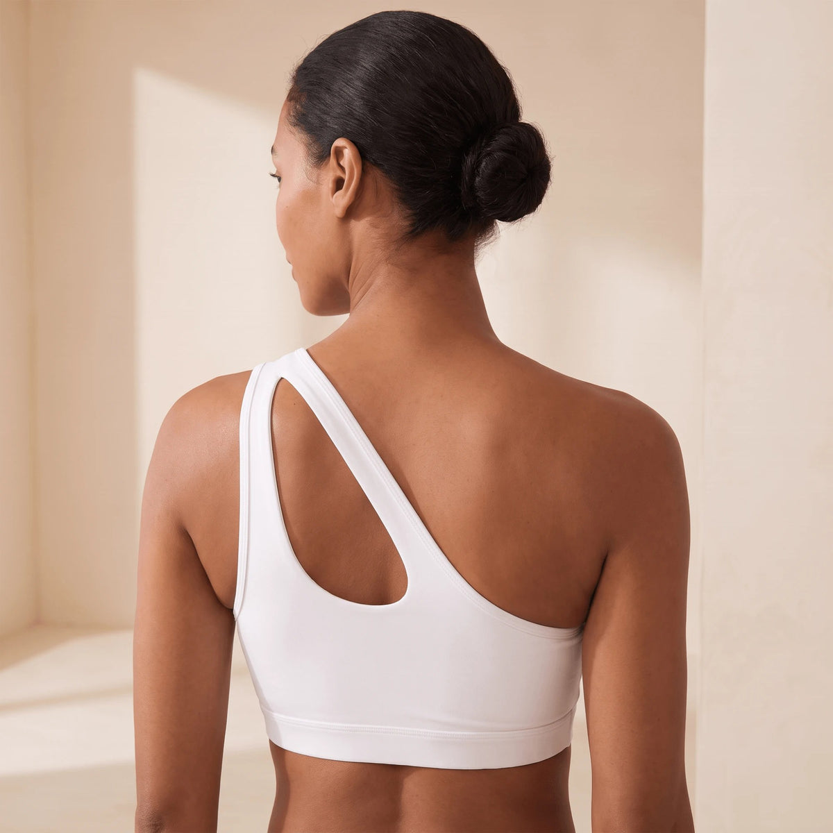 Dos d'une brassière de sport asymétrique blanche : bretelle unique et découpe au dos