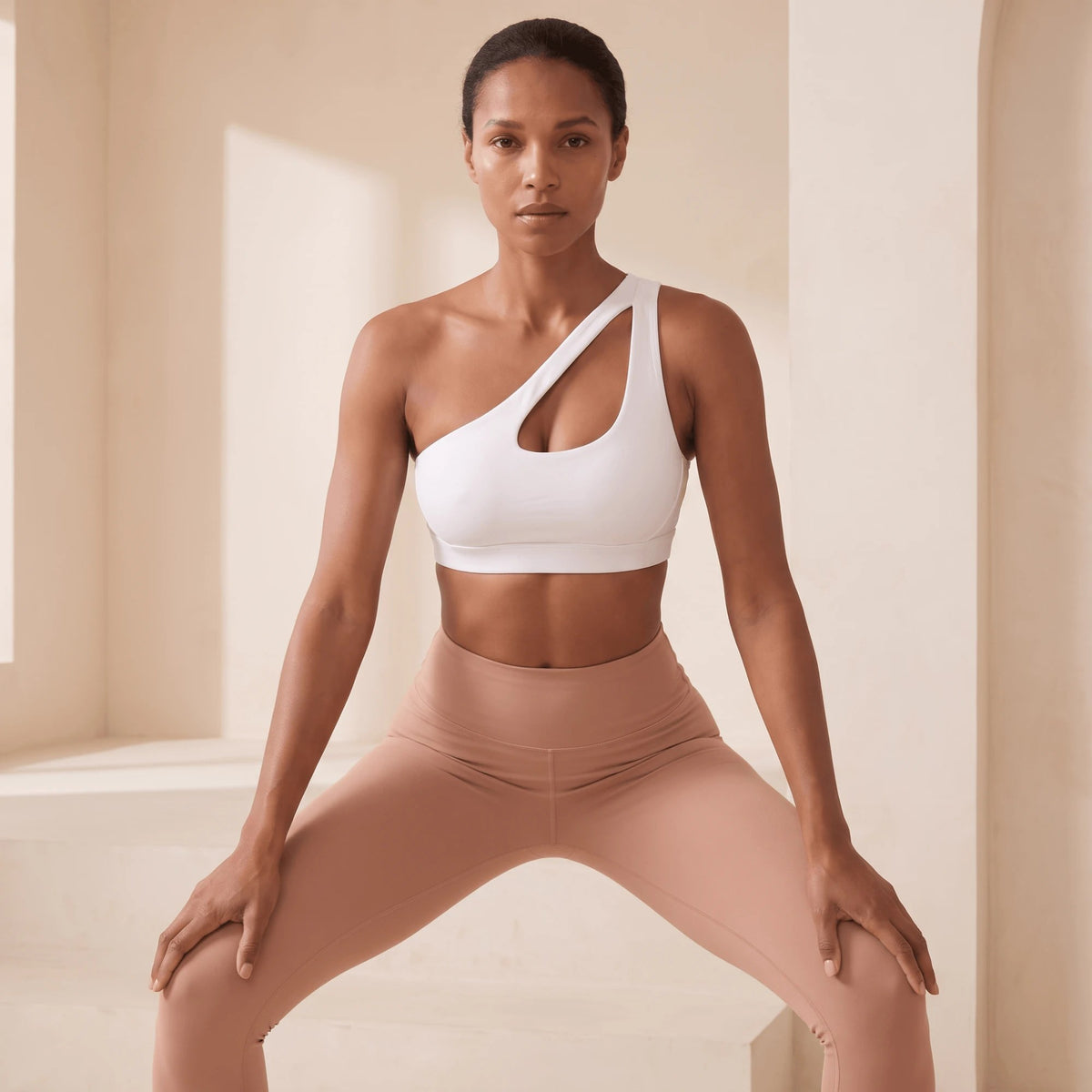 Brassière de sport blanche à une épaule en posture de fitness, jambes écartées