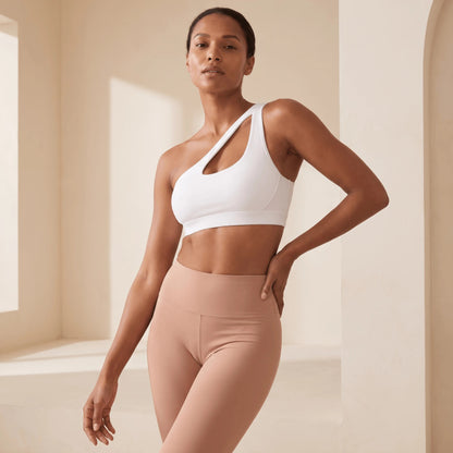 Brassière de sport asymétrique blanche une épaule, vue trois quarts, main sur la hanche