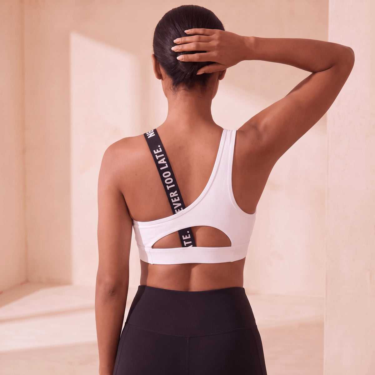 Brassière fitness dos nu blanche vue de dos, la bretelle à message traverse le dos