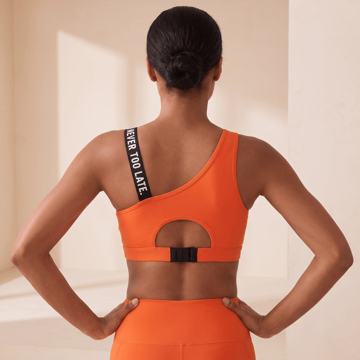 Brassière de sport orange dos nu avec découpe ronde et fermeture à agrafes dans le dos, bretelle à message