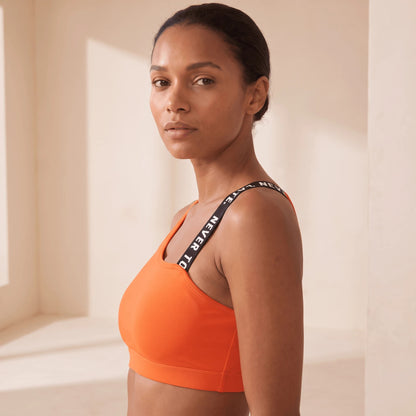 Brassière fitness orange vue de profil, bretelle à message et tenue ajustée sous la poitrine