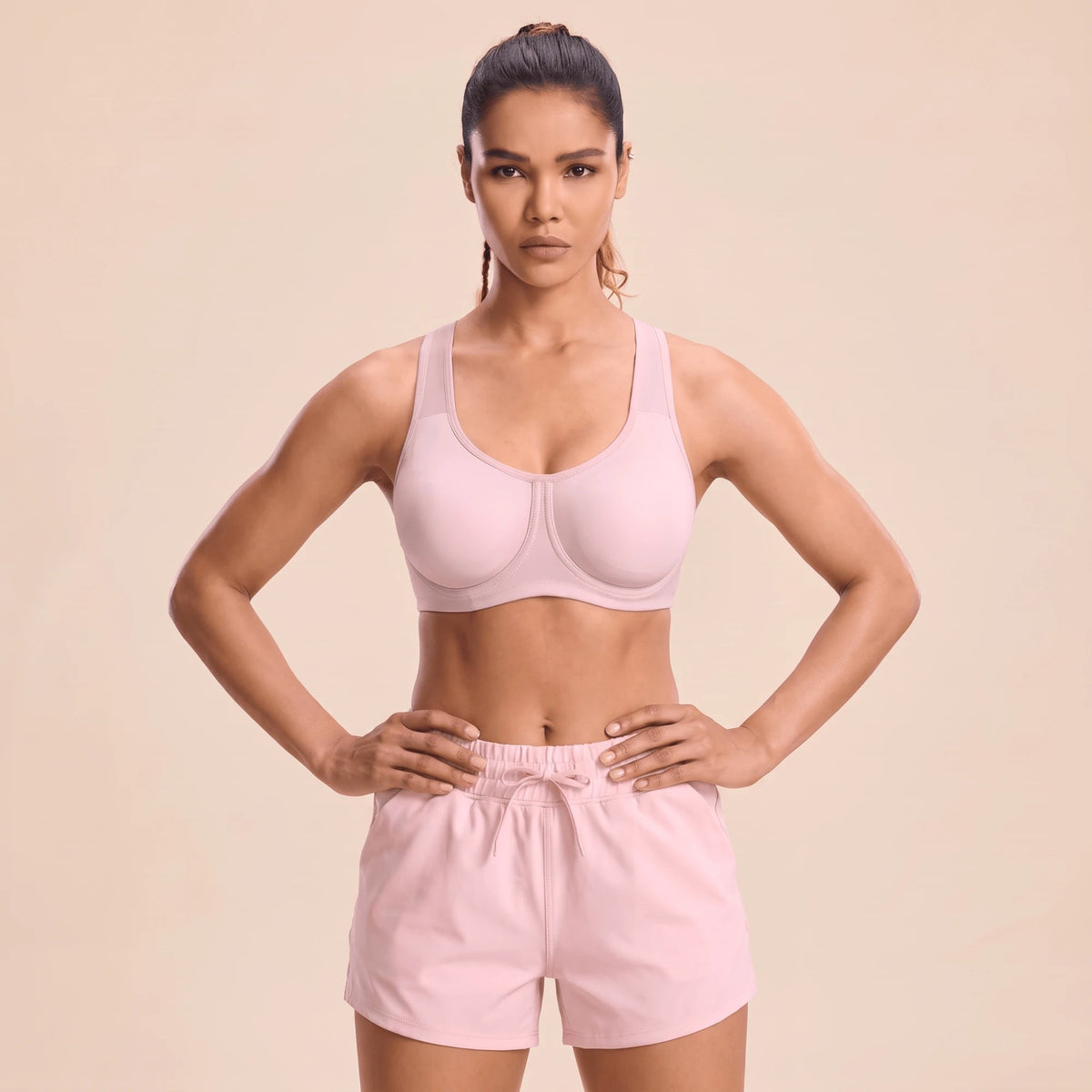 Femme en brassière fitness rose à armatures, mains sur les hanches