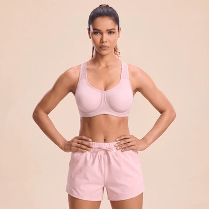 Femme en brassière fitness rose à armatures, mains sur les hanches