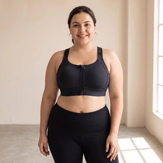 Brassière maintien fort grande taille noire à zip devant, portée de face dans un studio lumineux, bretelles réglables et large bande sous la poitrine