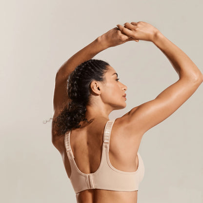 Dos d'une brassière de running beige, bras levés, bretelles réglables et fermeture à crochets