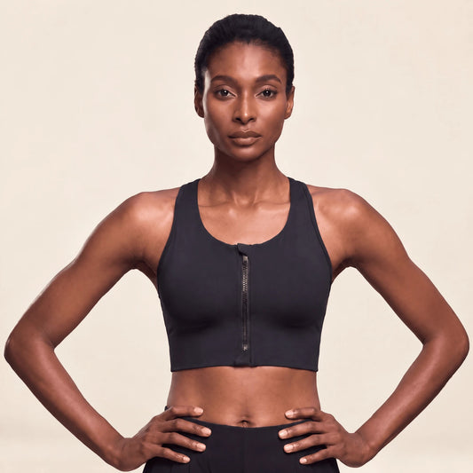 Brassière running grande taille noire à maintien fort et zip devant, portée de face, mains sur les hanches