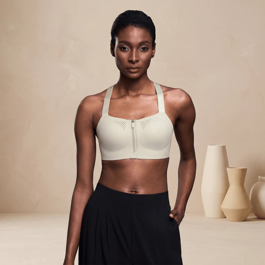 Brassière sport femme à bretelles croisées et fermeture éclair devant, coloris blanc fleur de poirier, portée de face en plan buste