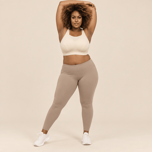Brassière de sport grande taille creme bras levés – liberté de mouvement totale, maintien renforcé forte poitrine, coupe seamless sculptante, femme pulpeuse blonde carré wavy rouge à lèvres en studio ivoire