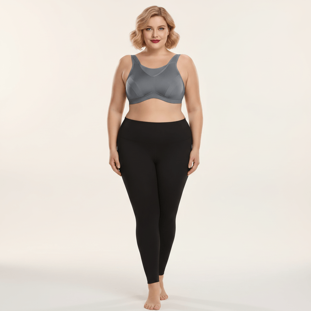 Brassière de sport grande taille grise vue de face – maintien renforcé forte poitrine, coupe seamless sculptante, femme pulpeuse blonde carré wavy rouge à lèvres en studio ivoire