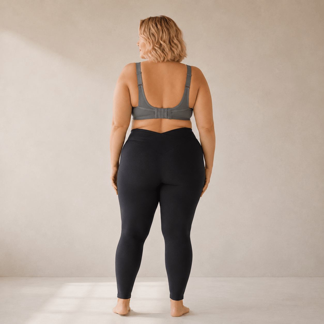 Brassière de sport grande taille blanche vue profil trois-quarts – maintien renforcé, coupe seamless sculptante, femme pulpeuse blonde carré wavy rouge à lèvres en studio crème