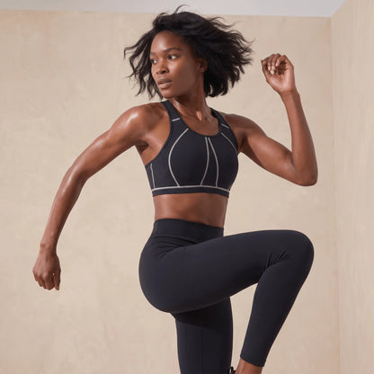 Femme en mouvement portant la brassière fitness noire pendant un exercice dynamique