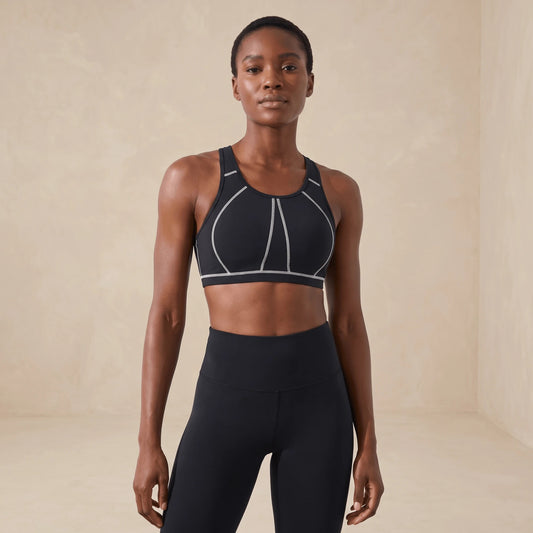 Brassière fitness noire à coutures blanches, dos nageur, portée de face avec un legging noir