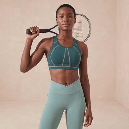 Brassière de sport vert canard à coutures beiges, portée avec un legging vert, raquette de tennis
