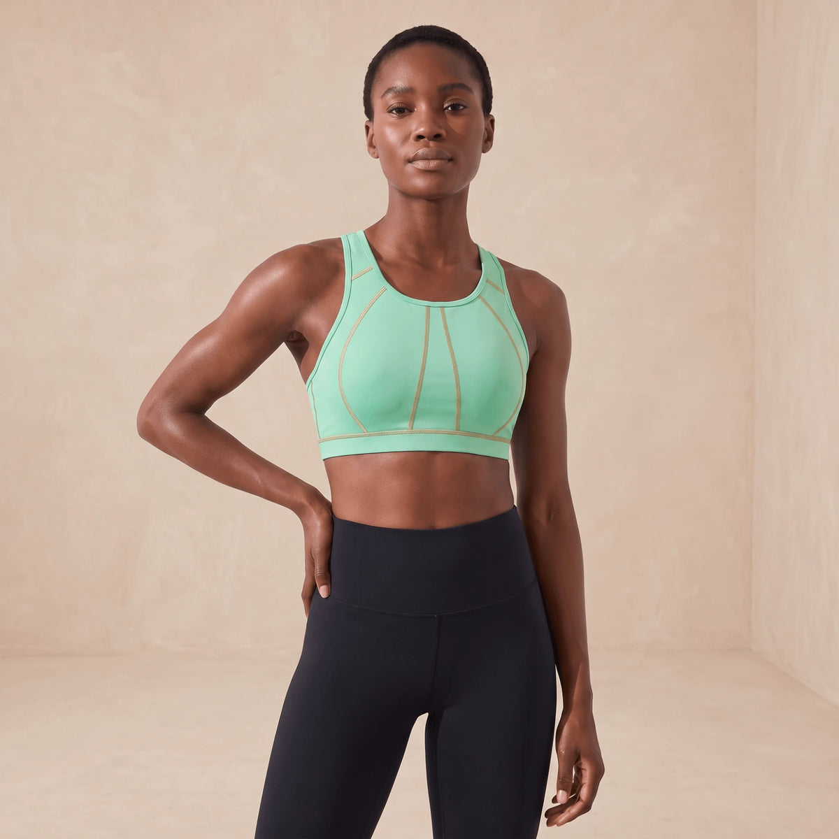 Brassière de sport vert menthe à coutures dorées, portée de face