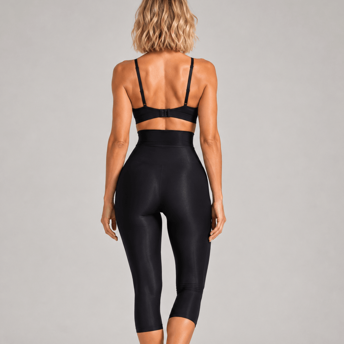Collant anti cellulite noir vue de dos, effet galbant, taille haute, studio gris clair uniforme.