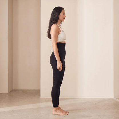 Collant gainant ventre plat noir vu de profil, ceinture haute au-dessus du nombril, studio beige crème