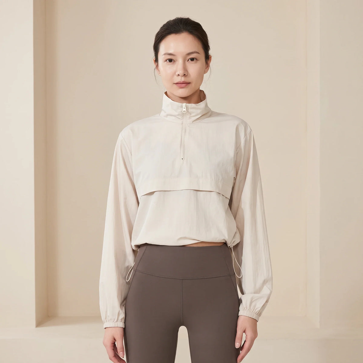 Coupe-vent femme court beige porté de face, col montant zippé et ourlet à cordon réglable