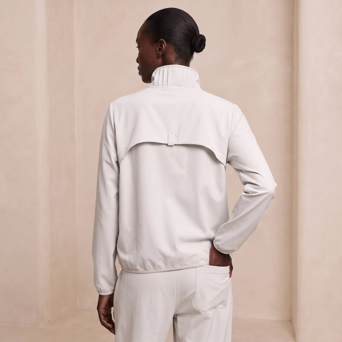 Coupe-vent femme running pliable ivoire vu de dos, empiècement et ourlet resserré