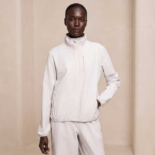 Coupe-vent femme running pliable ivoire porté de face, col montant et zip intégral