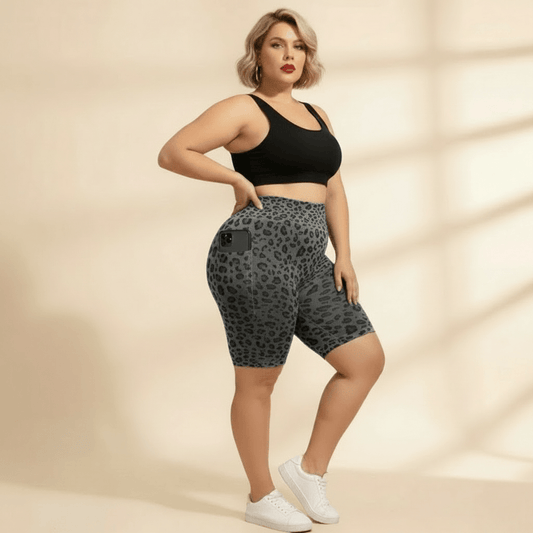 Cycliste sport grande taille imprimé léopard gris et noir seamless taille haute gainant, avec poches téléphone vue de face trois-quarts main sur la hanche, fond studio crème