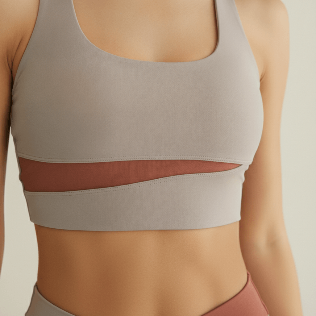 Ensemble yoga femme — zoom brassière gris clair bande terracotta croisée, détail tissu bicolore studio