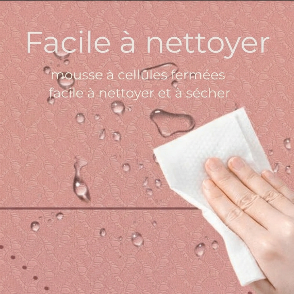 Gros plan du tapis Asana Aura rose poudré avec gouttes d’eau et main essuyant, texte “Facile à nettoyer – mousse à cellules fermées