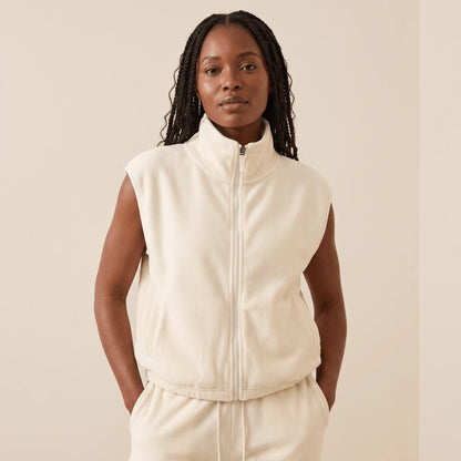 Gilet polaire sans manche femme blanc crème, col montant et zip intégral, porté de face sur un jogging assorti