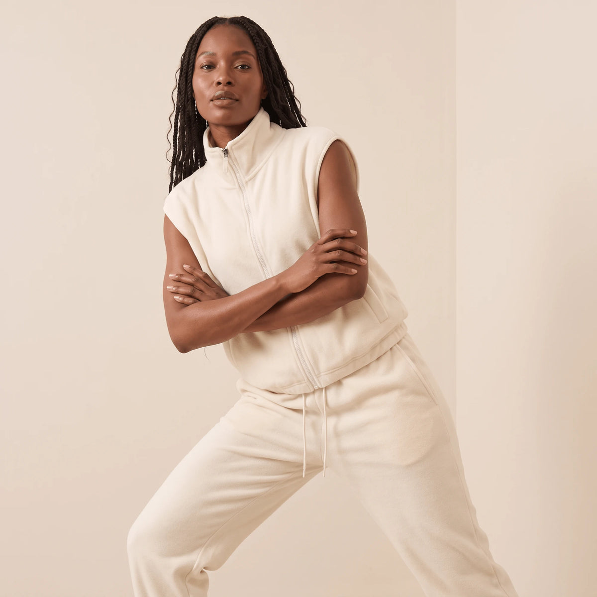 Gilet sans manche femme polaire blanc crème, pose dynamique de sport, cordon à l'ourlet et col montant