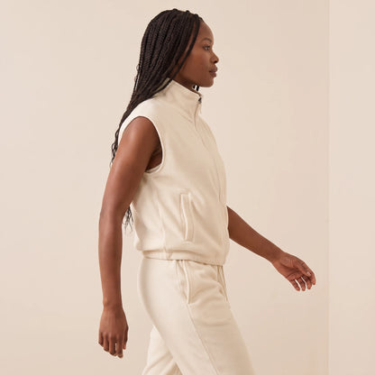 Gilet polaire femme blanc crème vu de profil en marche : poche latérale, emmanchure et ourlet resserré