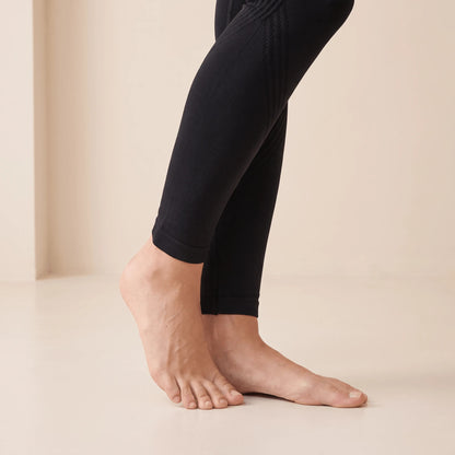 Détail du motif en vagues sur le mollet d'un legging noir sans couture qui dessine la jambe, maille fine et lisse