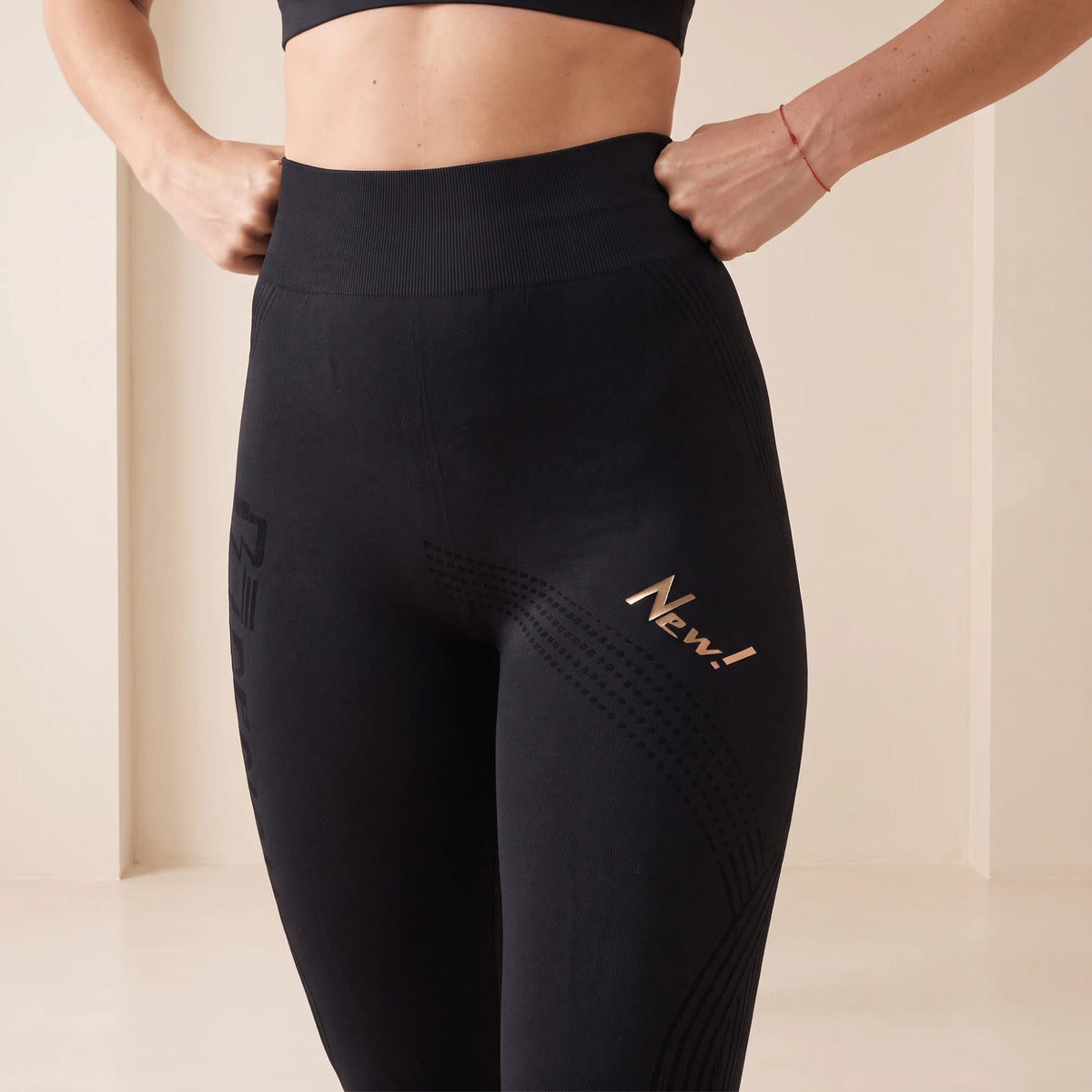 Gros plan sur la taille et la cuisse d'un legging anti cellulite noir : motif en points et lignes en vagues, ceinture côtelée