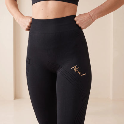 Gros plan sur la taille et la cuisse d'un legging anti cellulite noir : motif en points et lignes en vagues, ceinture côtelée