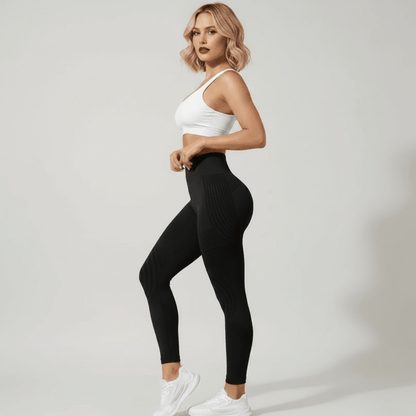 Legging anti cellulite noir taille haute, vue de profil avec brassière blanche, studio ivory gray, femme blonde.