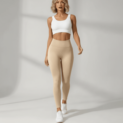 Legging anti cellulite nude vue de face, pose élégante, brassière blanche, studio ivory gray, femme blonde.